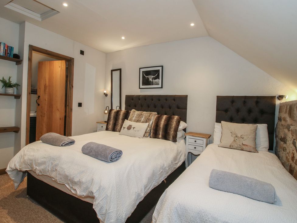 A bedroom with two beds and a door at Corn House in Cardington