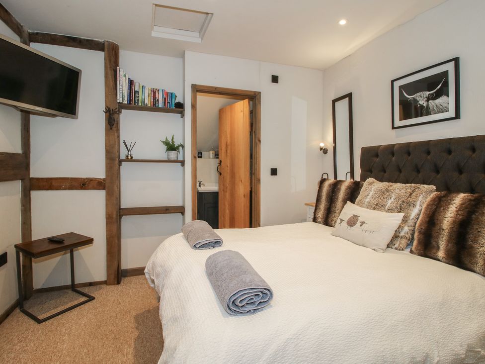 A bedroom with a bed and bookshelf at Corn House in Cardington