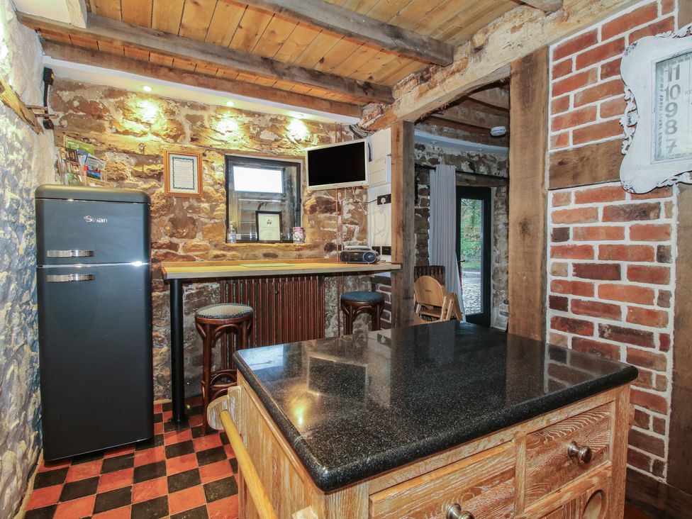 A kitchen with a black refrigerator and bar counter in Corn House Cardington