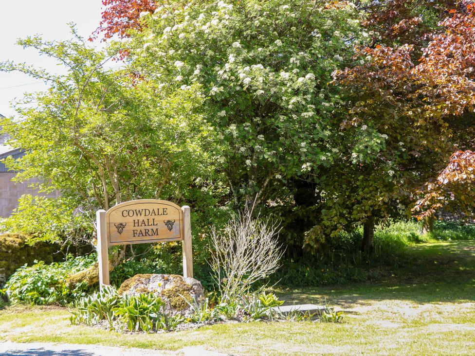 A sign with Cowdale Hall Farm near trees and plants at The Shavings in Cowdale near Buxton