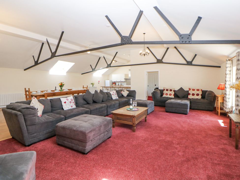 A large open living room with gray sofas and ottomans on a red carpet at Woodlands in Cowdale near Buxton