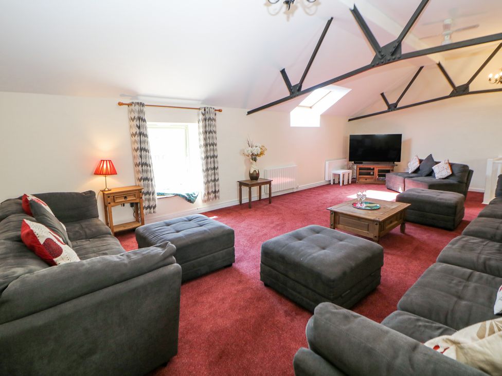 A living room with gray sofas red carpet and a television at Woodlands in Cowdale near Buxton