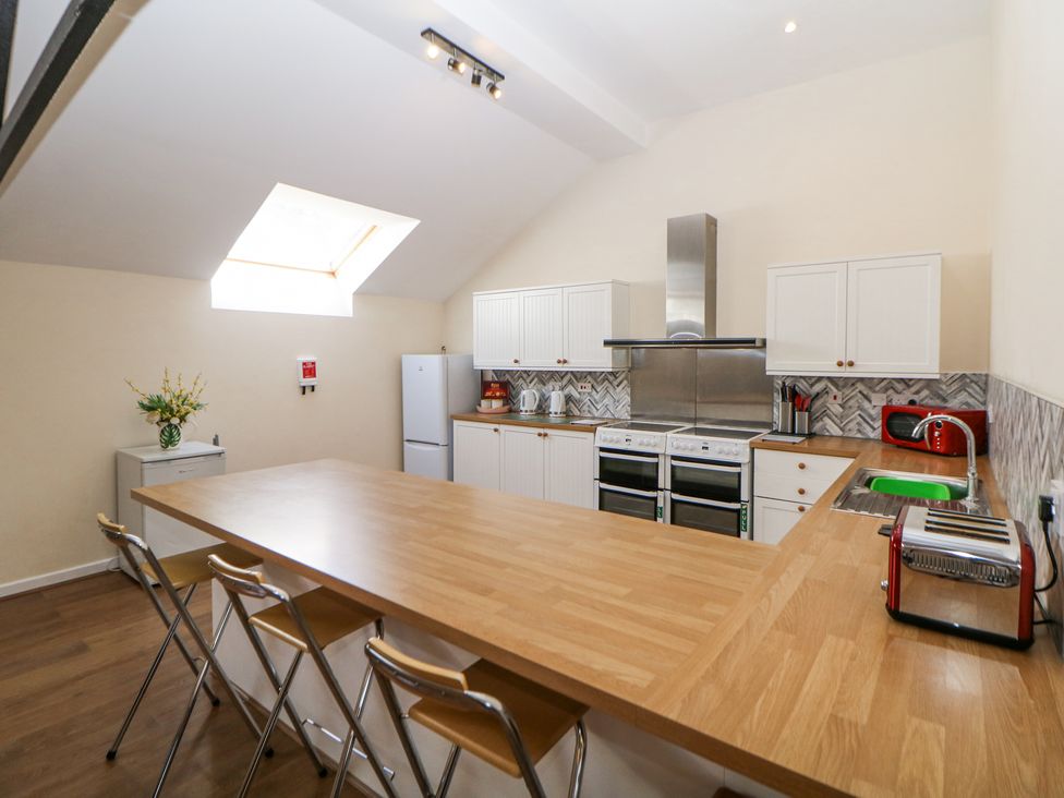 A kitchen with wooden countertops stools refrigerator stove and toaster at Woodlands in Cowdale near Buxton