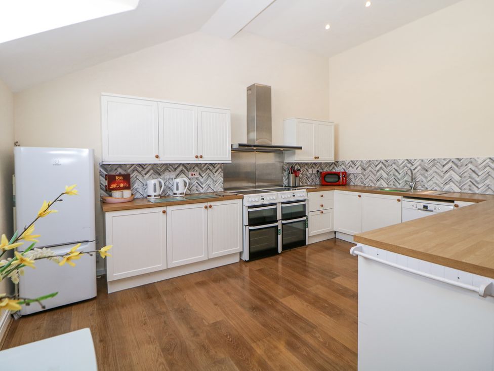 A kitchen with white cabinets wooden countertops double ovens a refrigerator and a red microwave at Woodlands in Cowdale near Buxton