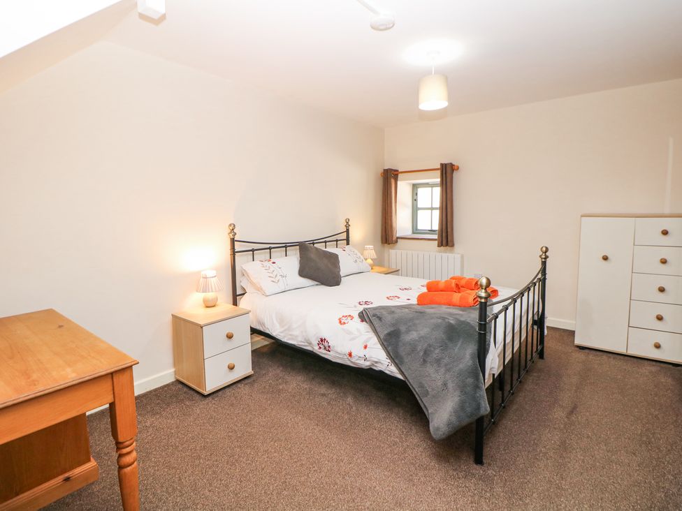 A bedroom with a double bed bedside tables lamps a wooden desk and a chest of drawers at Woodlands Cowdale near Buxton