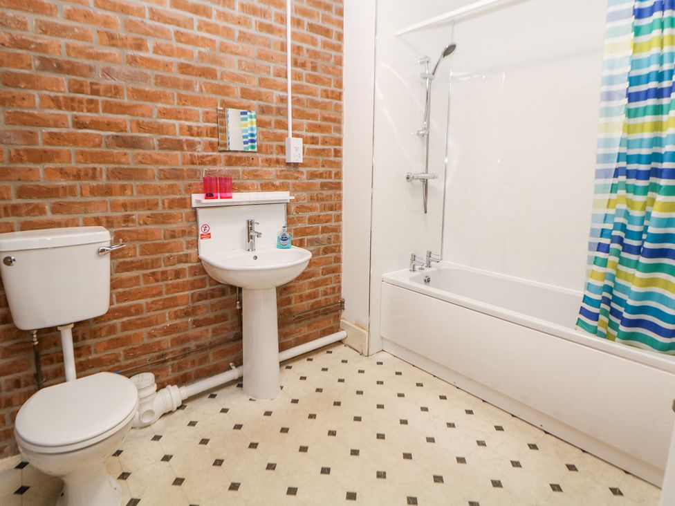 A bathroom with a toilet sink bathtub and colorful shower curtain at Woodlands in Cowdale near Buxton