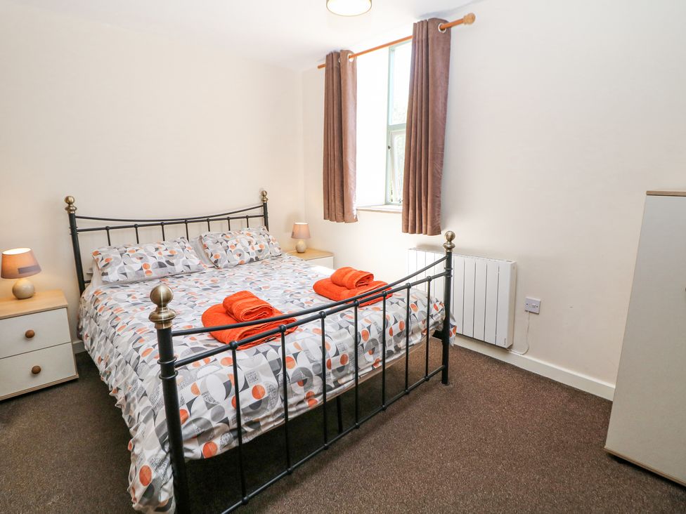 A bedroom with a black metal bed frame two bedside tables with lamps and folded orange towels on the bed at Woodlands in Cowdale near Buxton