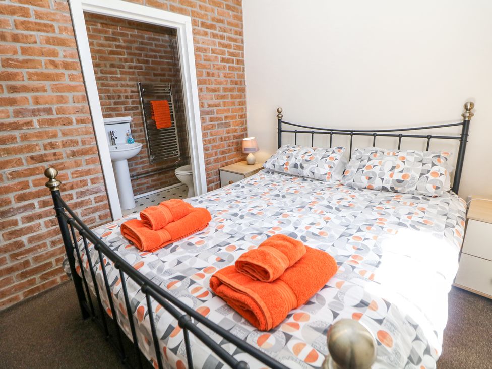 A bedroom with a double bed and orange towels in front of an ensuite bathroom at Woodlands in Cowdale near Buxton