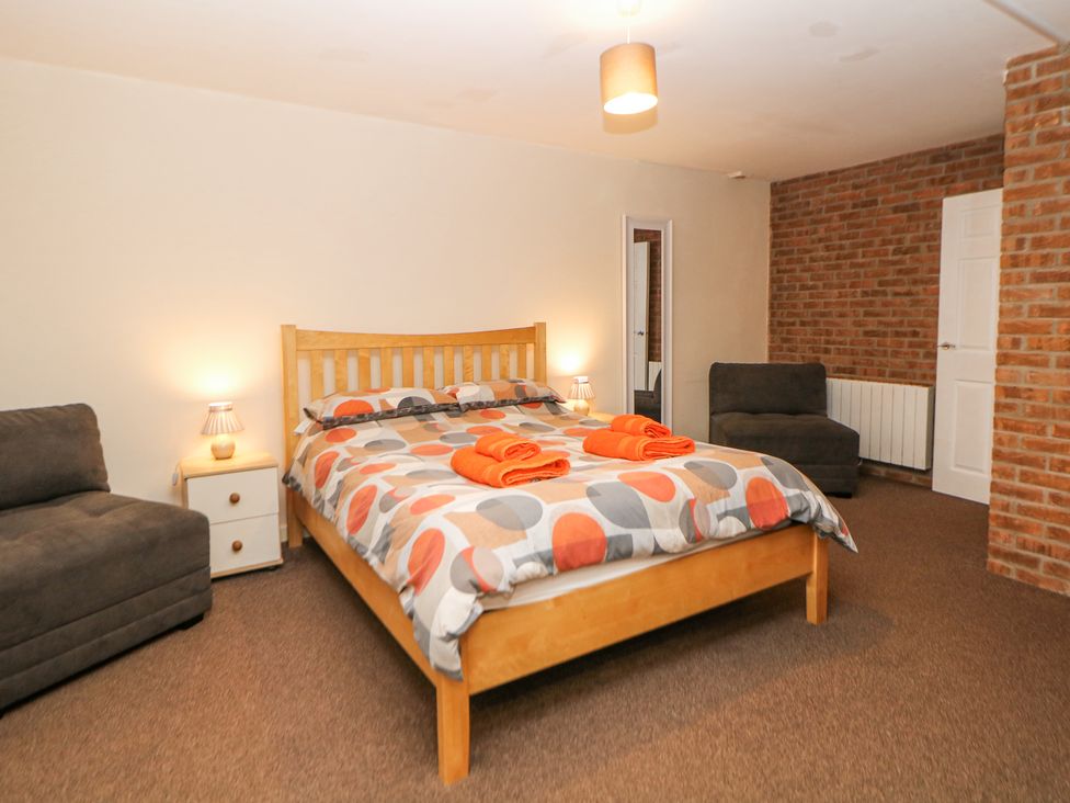 A bedroom with a wooden bed with polka dot bedding two brown chairs and bedside tables at Woodlands in Cowdale near Buxton