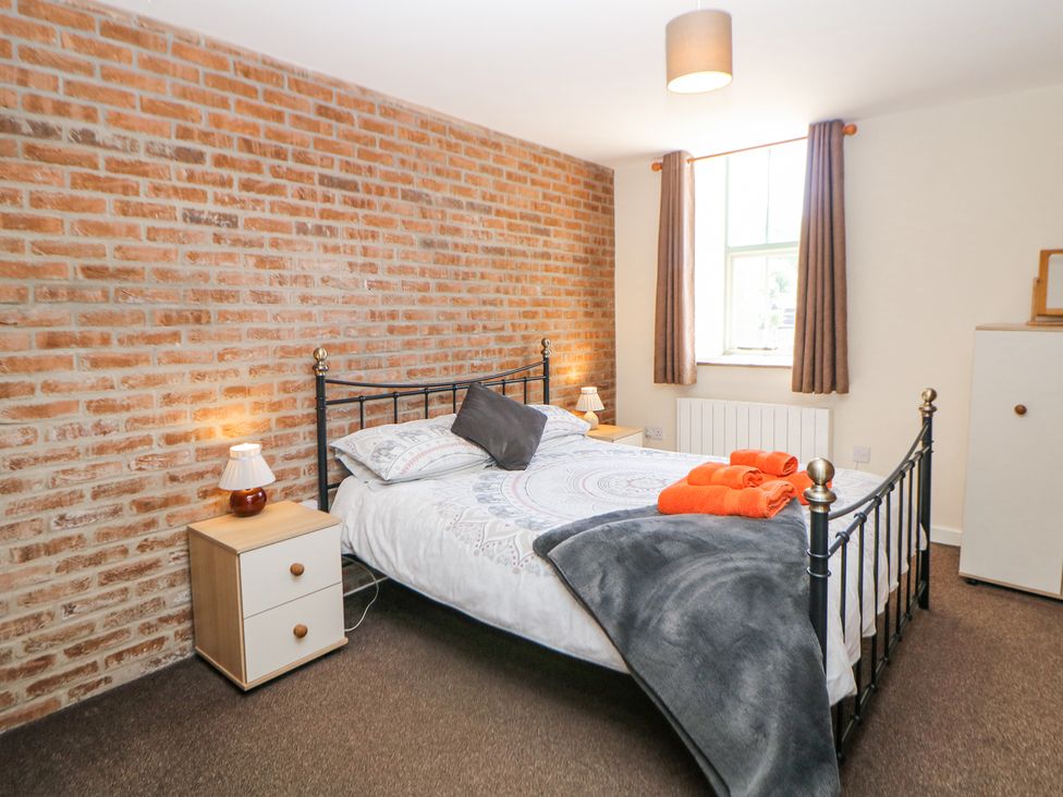 A bedroom with a double bed with patterned bedding and orange towels on the bed at Woodlands in Cowdale near Buxton