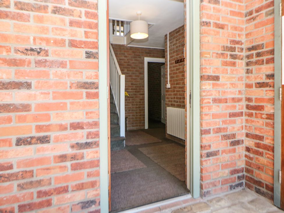 An entrance hallway with carpeted floor stairs and brick walls at Woodlands in Cowdale near Buxton