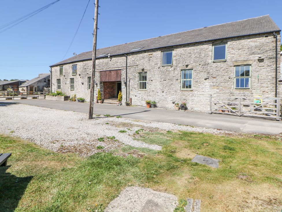 Stone barn style building with multiple windows and potted plants in front at Woodlands in Cowdale near Buxton
