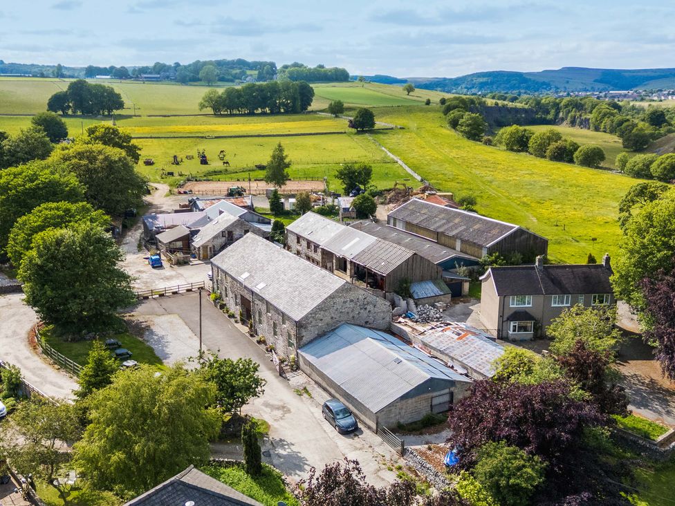 An aerial view of farmland with barns and vehicles at Woodlands in Cowdale near Buxton