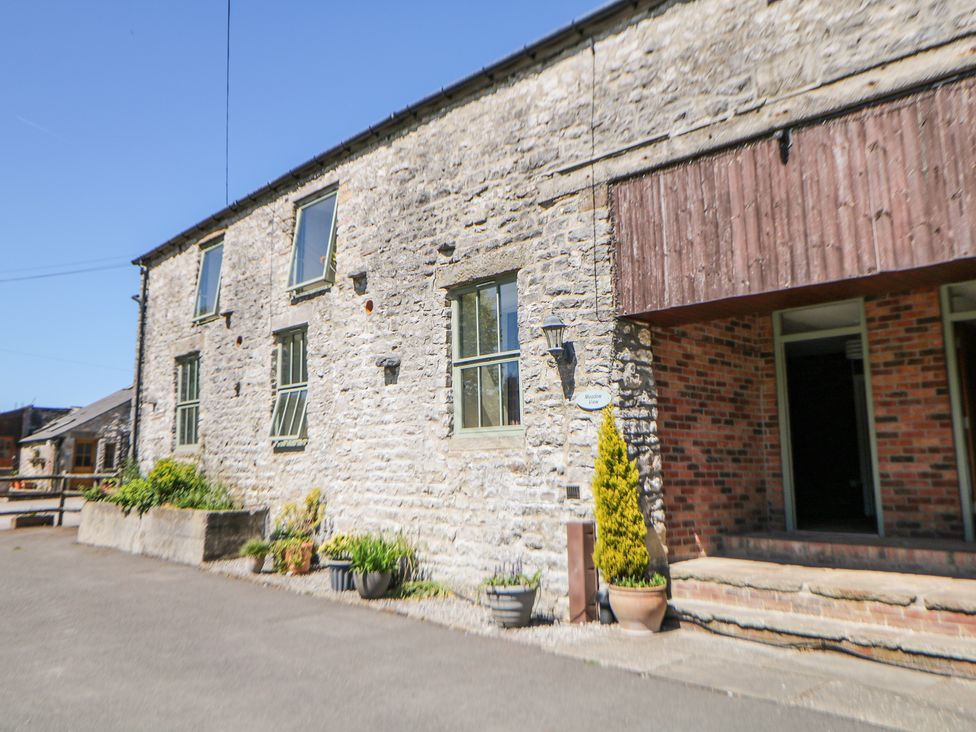 The exterior of a stone building with multiple windows and potted plants near the entrance at Meadow View in Buxton