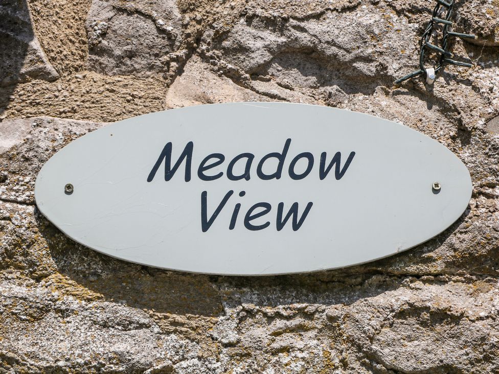 An oval sign with Meadow View mounted on a stone wall Meadow View Buxton