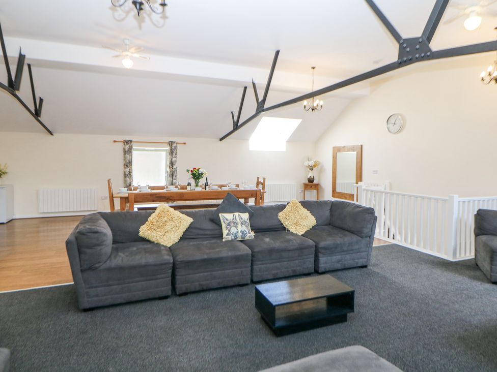 A living area with a gray sectional sofa and coffee table next to a dining table with chairs and table setting at Meadow View in Buxton