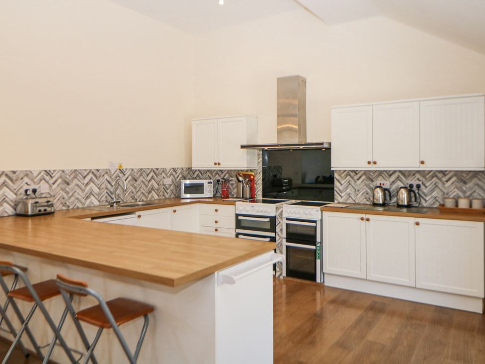 A kitchen with white cabinets wooden countertops two ovens and bar stools at Meadow View in Buxton