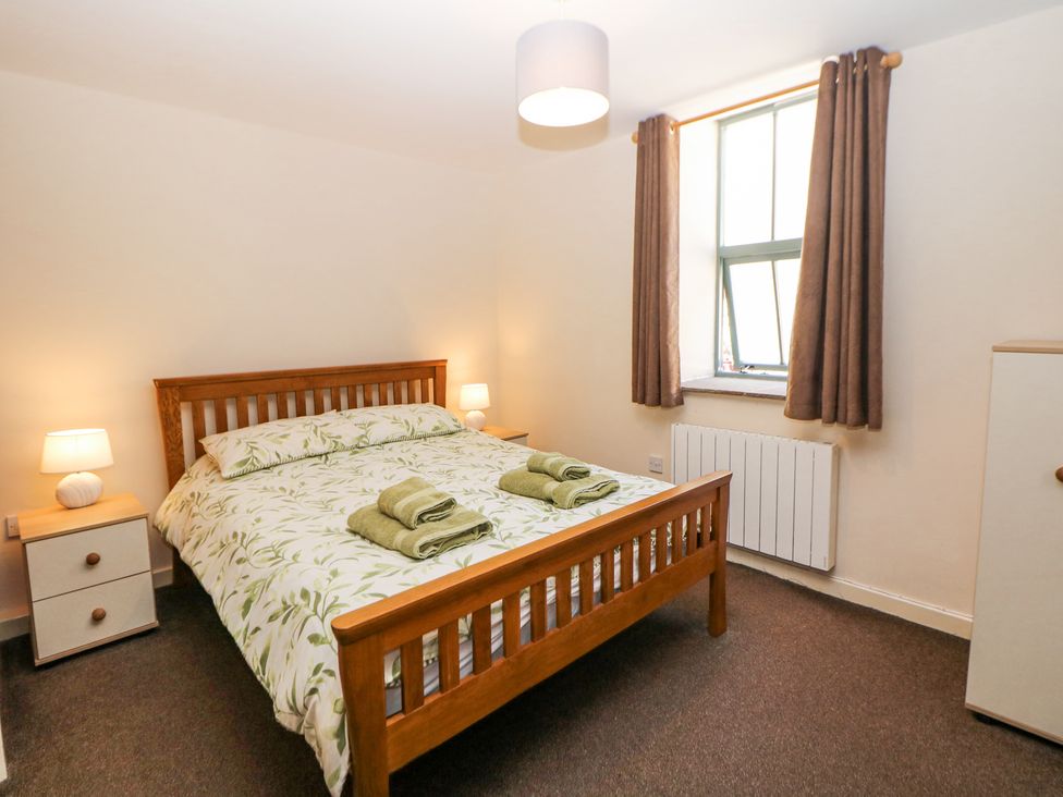 A bedroom with a wooden bed and two bedside tables with lamps at Meadow View in Buxton