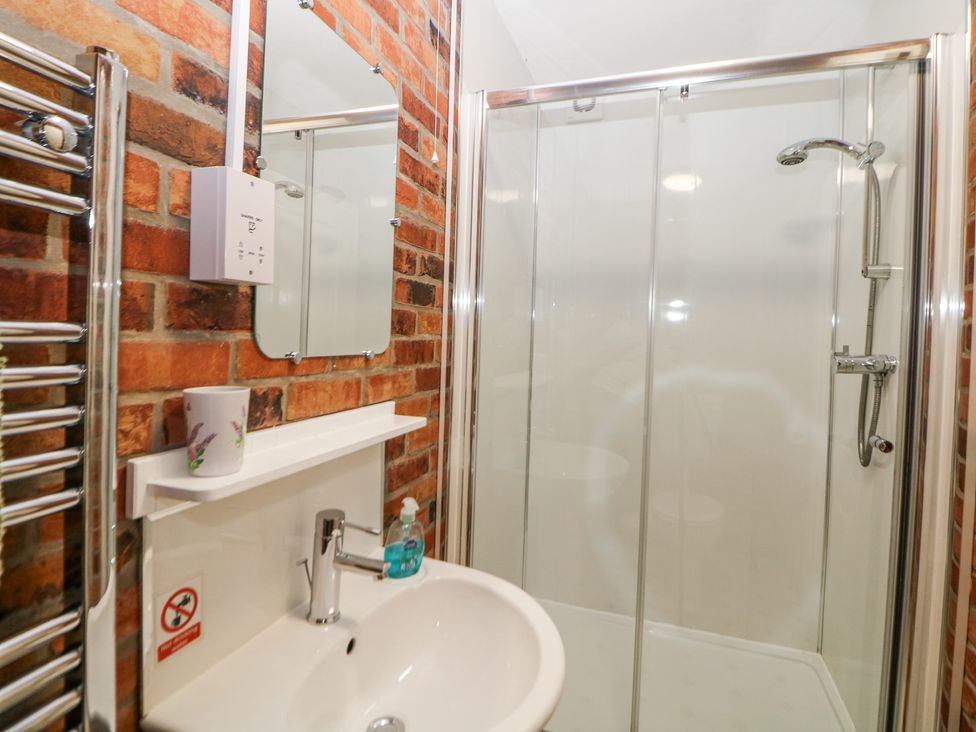 A bathroom with a sink and faucet a mirror a soap dispenser and a shower cubicle with glass sliding doors at Meadow View in Buxton
