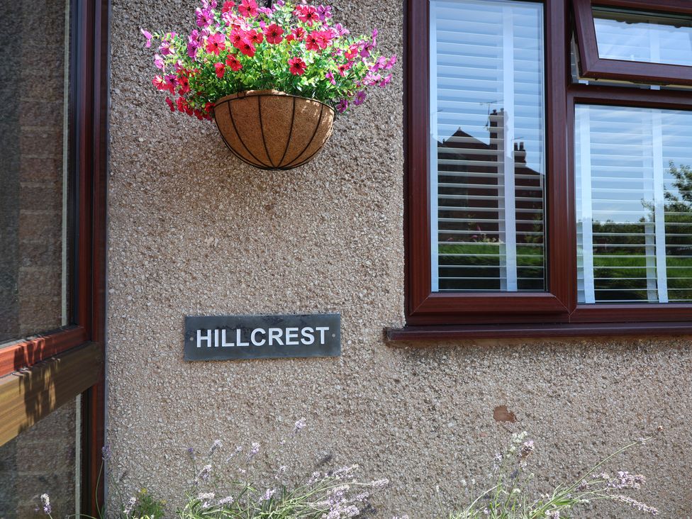 A flower basket and sign on an exterior wall at Hillcrest in Cefn Mawr near Chirk