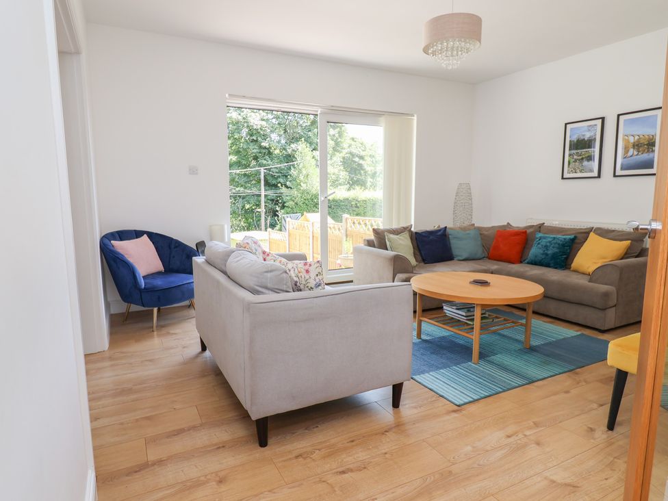 A living room with a blue armchair and grey sofa at Hillcrest in Cefn Mawr near Chirk
