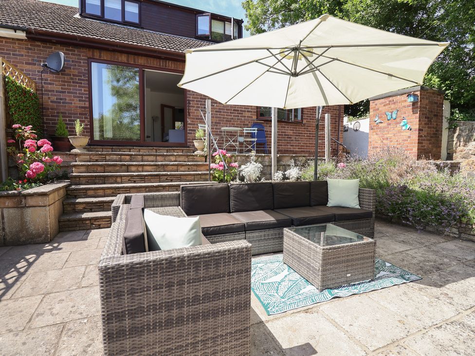 A garden with outdoor sofa and umbrella at Hillcrest in Cefn Mawr near Chirk