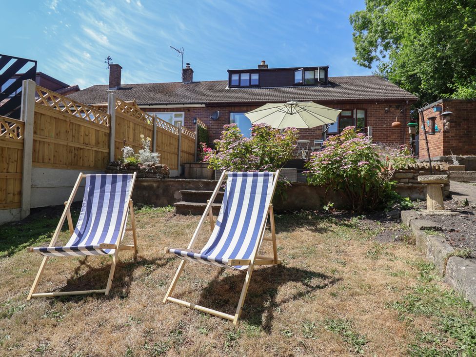 A garden with deck chairs and an umbrella at Hillcrest in Cefn Mawr near Chirk