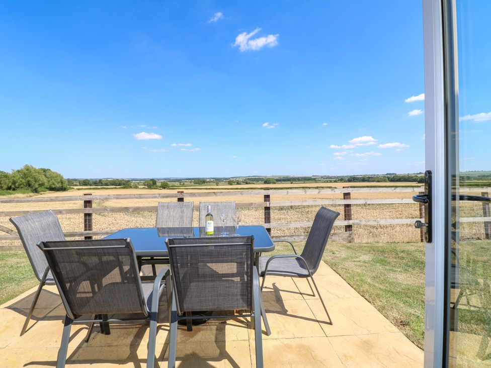 A table with chairs and a bottle in an outdoor area at Teal Cottage in Melton Mowbray