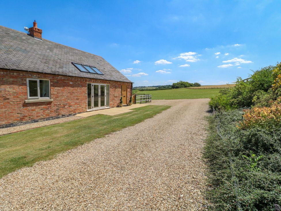 A house with a gravel driveway and fields at Teal Cottage in Melton Mowbray