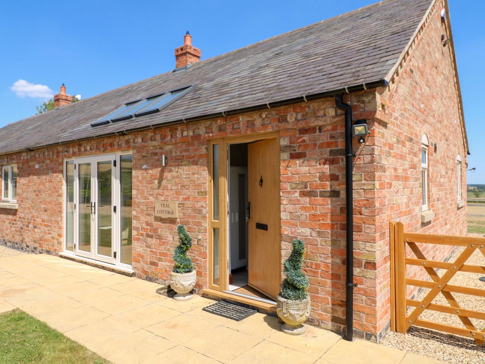 A brick exterior with double doors and a sign at Teal Cottage Melton Mowbray