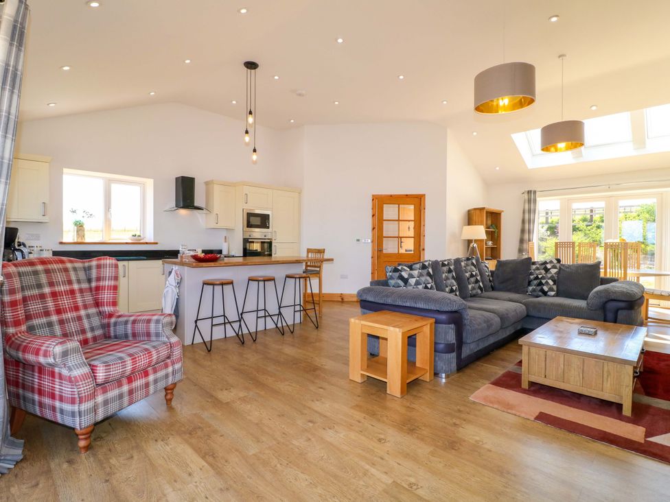 A living room with a sofa, coffee table, and kitchen island at Teal Cottage in Melton Mowbray