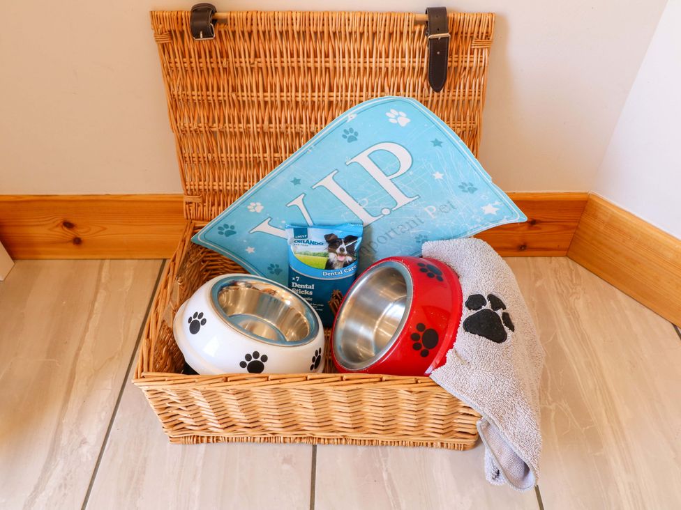 A basket containing pet bowls, dental sticks, and a towel at Teal Cottage Melton Mowbray