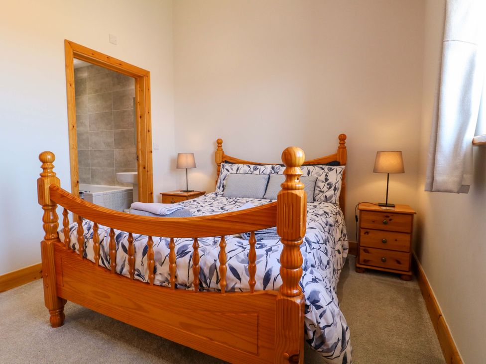 A bedroom with a bed and a doorway to a bathroom at Teal Cottage Melton Mowbray