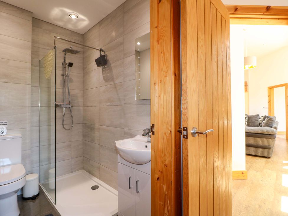 A bathroom with shower, toilet, sink, and wooden door at Teal Cottage, Melton Mowbray