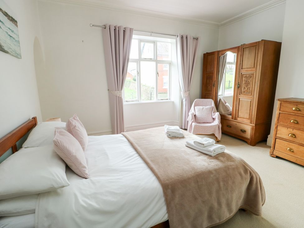 A bedroom with a bed, wardrobe, and chair at Preswylfa in Caernarfon