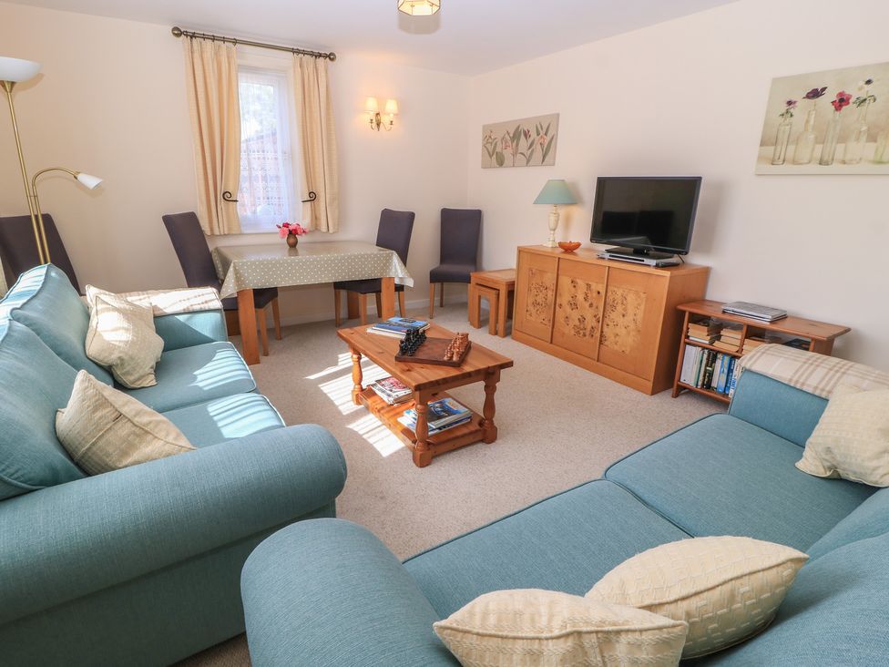 A living room with a sofa, TV, and a dining table at Willow Barn in Cucklington near Wincanton