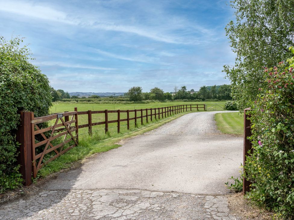 A gravel road with a gate and fence at Little Barn in Cucklington near Wincanton