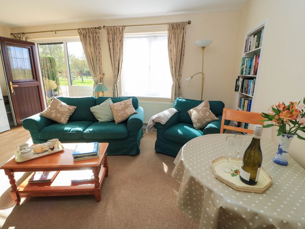 A living room with a sofa, table, and bookshelf at Little Barn in Cucklington near Wincanton