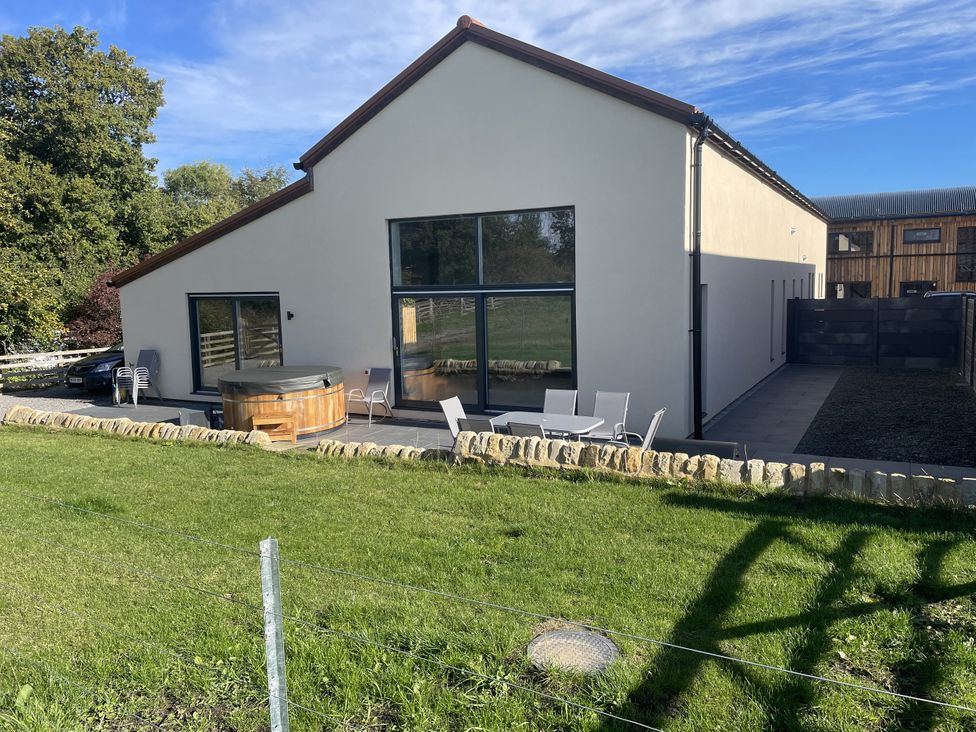 An outdoor area with a hot tub and seating at 1 New Dairy Barn