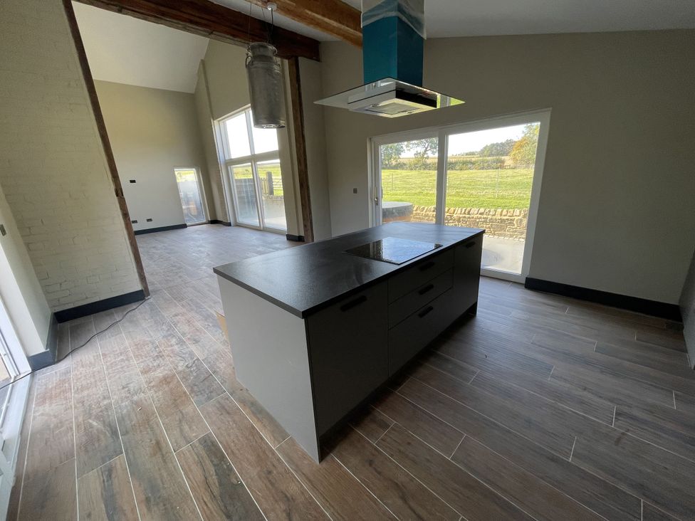 A kitchen with a central island and large windows at 1 New Dairy Barn