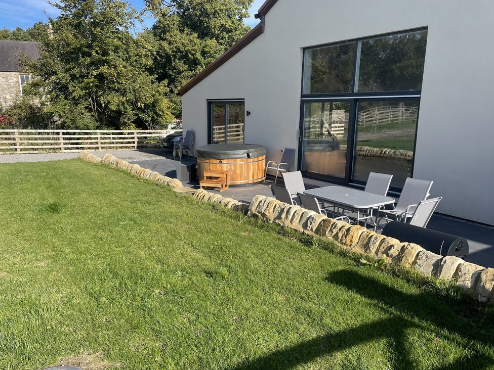 An outdoor area with a hot tub and seating at 1 New Dairy Barn
