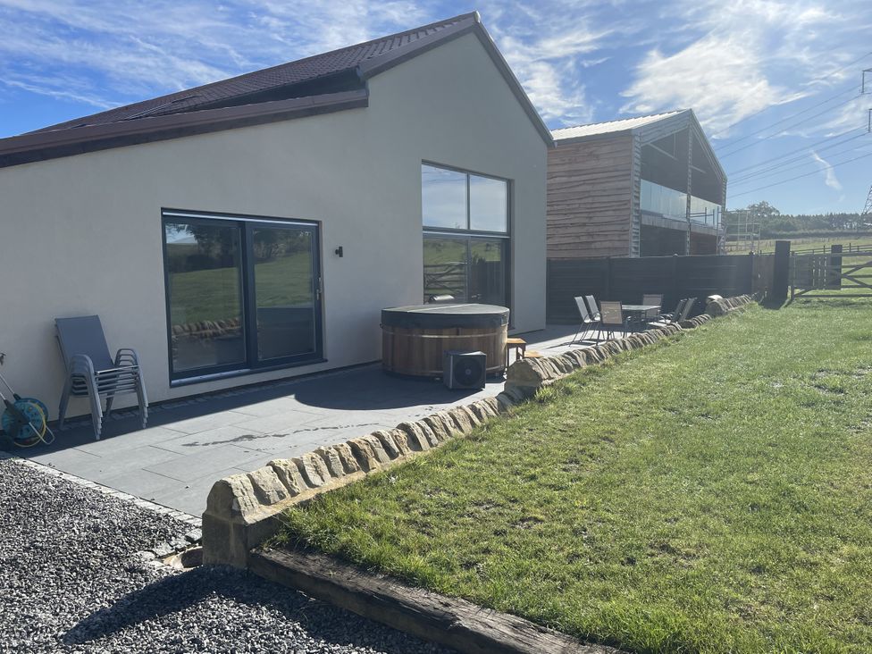 An outdoor area with a house, hot tub, and lawn at 1 New Dairy Barn