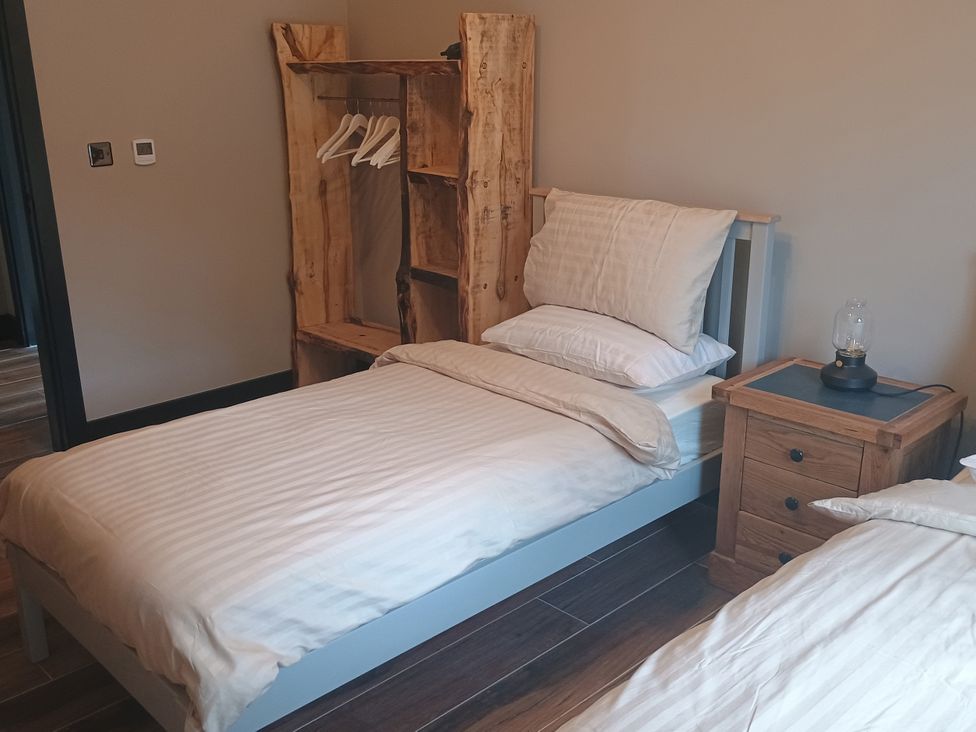 A bedroom with a bed and wooden shelf at 1 New Dairy Barn Croxdale