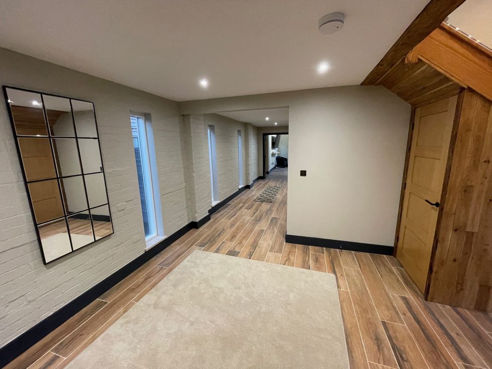 A hallway with a mirror and windows at 1 New Dairy Barn in Croxdale