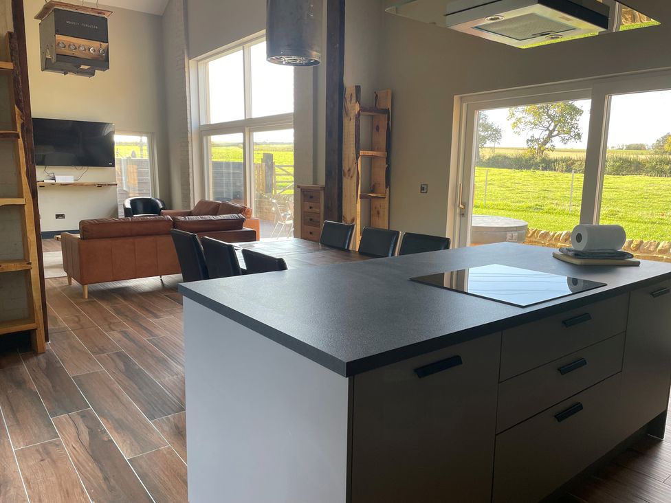 A kitchen with an island, chairs, and a television at 1 New Dairy Barn in Croxdale