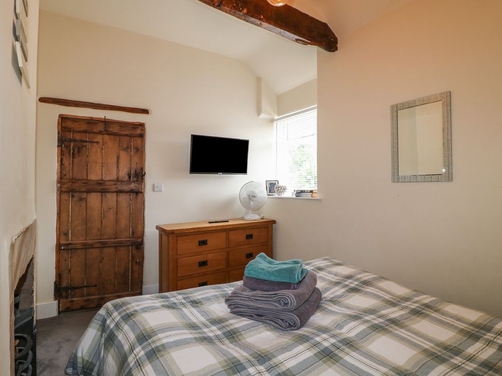 A bedroom with a bed, towels on top and a television on the wall at Milford Cottage in Milford near Duffield