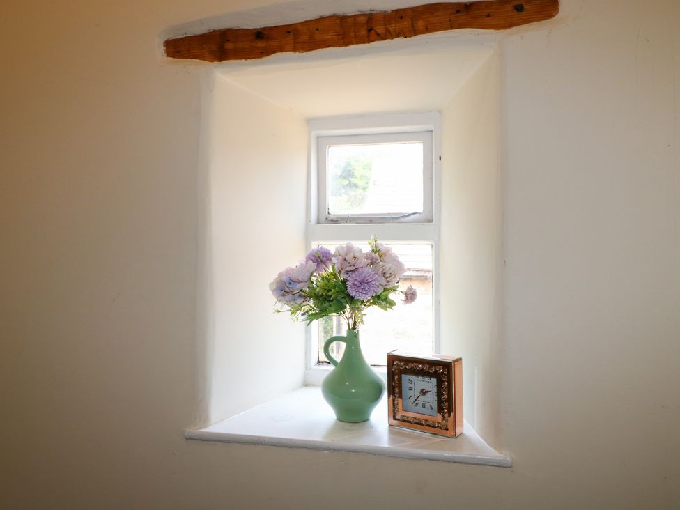 A window with a vase of flowers and a clock at Milford Cottage in Milford near Duffield