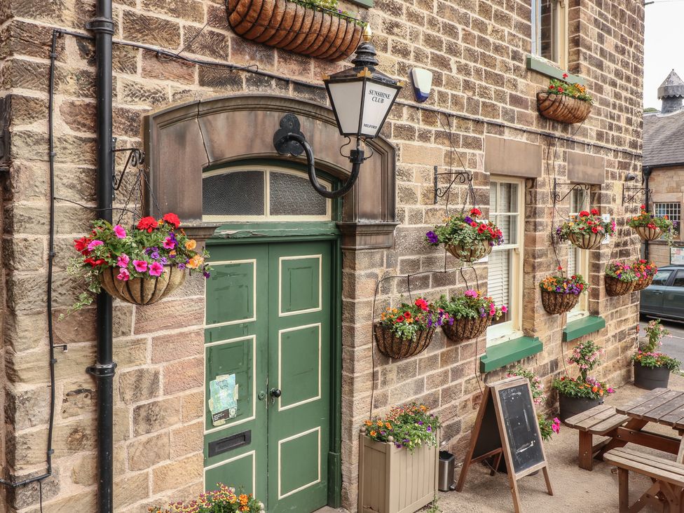 An entrance with green door and hanging flower baskets at Milford Cottage in Milford near Duffield