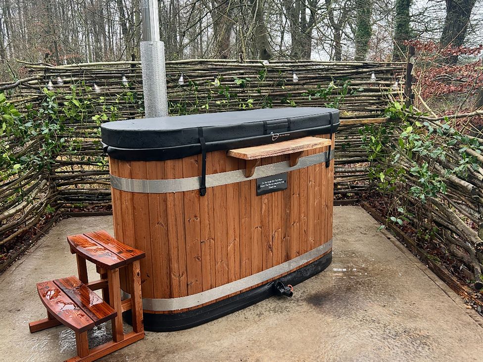 A wooden hot tub with a stool on a stone patio at Bracken Fern in Eppleby
