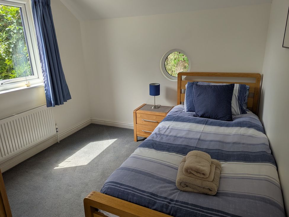 A bedroom with a bed and nightstand at Hawthorn Cottage in St Teath